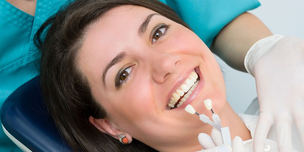 A woman is getting dental bonding done by a dentist.