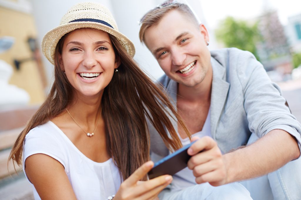 A man and woman are smiling while holding a dental bridge.